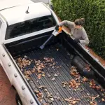 Vrouw ruimt bladeren op met BGA 30 bladblazer op een pick-up truck