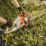 Een vrouw snoeit een haag met een STIHL HSE 52 heggenschaar