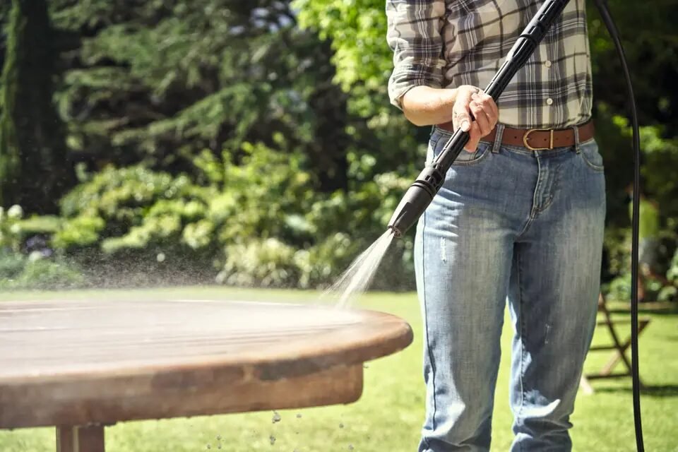 Vrouw reinigt tuintafel met STIHL RE 80 hogedrukreiniger