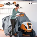 Vrouw bedekt STIHL RT 5097 Z zitmaaier met beschermhoes