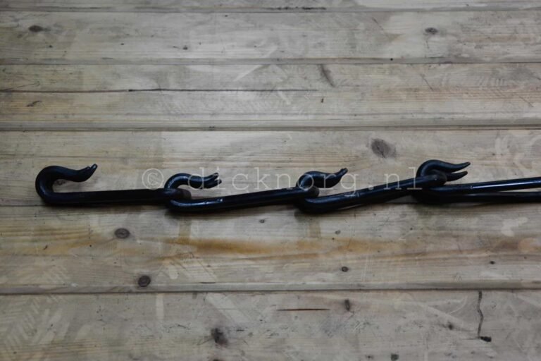 Detailopname van zwarte gesmede ketting met ronde schakels, liggend op een houten ondergrond.