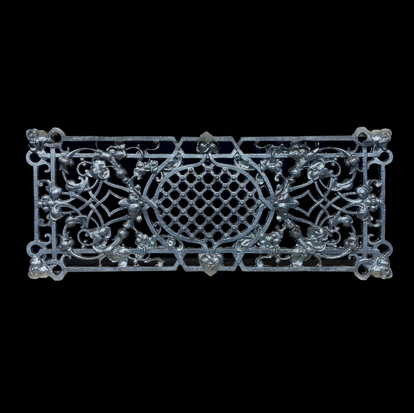 Een rechthoekig gietijzeren sierornament met een gedetailleerd patroon van bloemen, bladeren en een centraal ruitvormig raster, afgebeeld tegen een zwarte achtergrond.