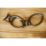 Gietijzeren sierketting bestaande uit drie in elkaar grijpende schakels, elk in de vorm van een gestileerde vis, liggend op een houten ondergrond.