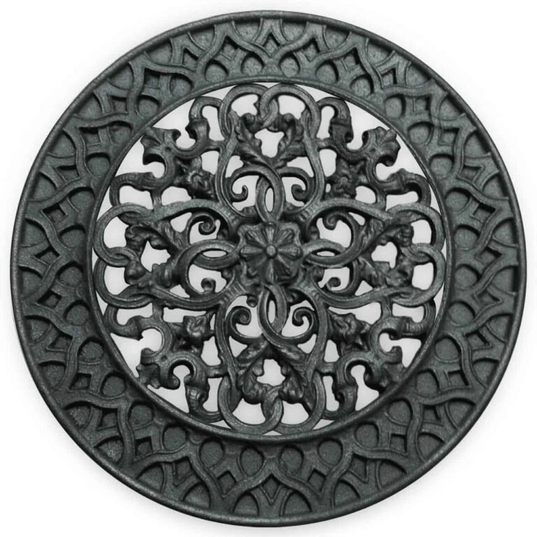 Rond gietijzeren ventilatorrooster met een gedetailleerd floraal en sierlijk ontwerp in het midden, omringd door een decoratieve rand, afgebeeld tegen een witte achtergrond.