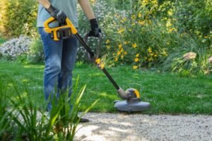 Persoon die de randen van een gazon trimt met de Stiga accugrastrimmer.