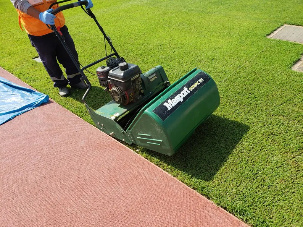 Masport kooimaaier in gebruik op een sportveld, met bediener in werkkleding