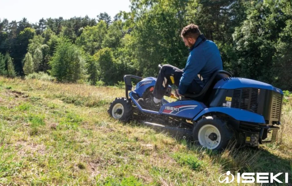 Bestuurder maait op een helling met de Iseki ruwterreinmaaier, achter hem staan bomen