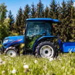 Iseki TG 6407 met cabine in een veld met bloemen, met een blauwe bak achterop