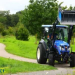 Iseki TG 6687 met cabine en frontlader met geheven bak op een pad