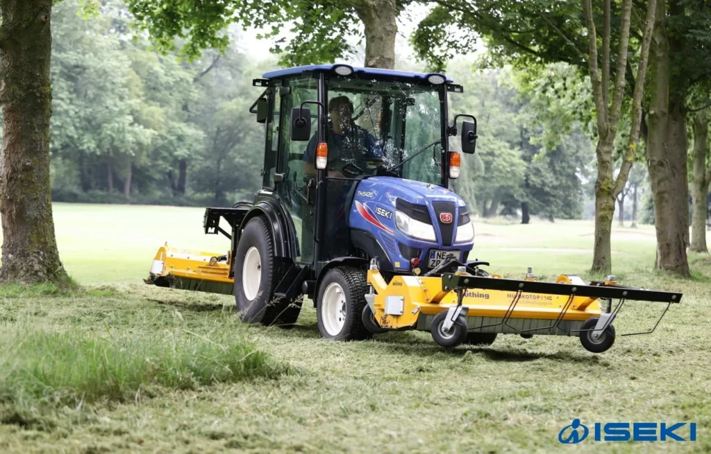 Iseki TH 5420 met cabine en een gele klepelmaaier op gras