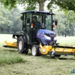 Iseki TH 5420 met cabine en een gele klepelmaaier achterop op gras