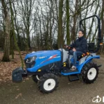 Iseki TM 4230 met beugel tussen bomen op een zandpad, met aanbouwdeel voorop