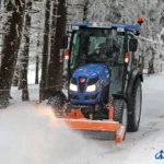 Iseki TG 6687 met cabine en een oranje sneeuwschuif voorop in een besneeuwd bos