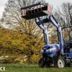 Iseki TH 5370 met veiligheidsbeugel en frontlader met geheven bak in een weiland