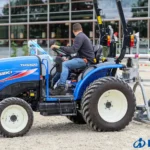 Iseki TH 5420 met veiligheidsbeugel en een zandhark achterop, met bestuurder