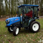 Bestuurder in rode jas in de cabine van de TM 4270 op een grasveld met bladeren