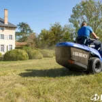 Achterkant van de Iseki zitmaaier met opvangbak vol gras, bestuurder maait voor een landhuis