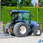 Iseki TG 6687 met cabine en brede banden die een werktuig achterop trekt over zand