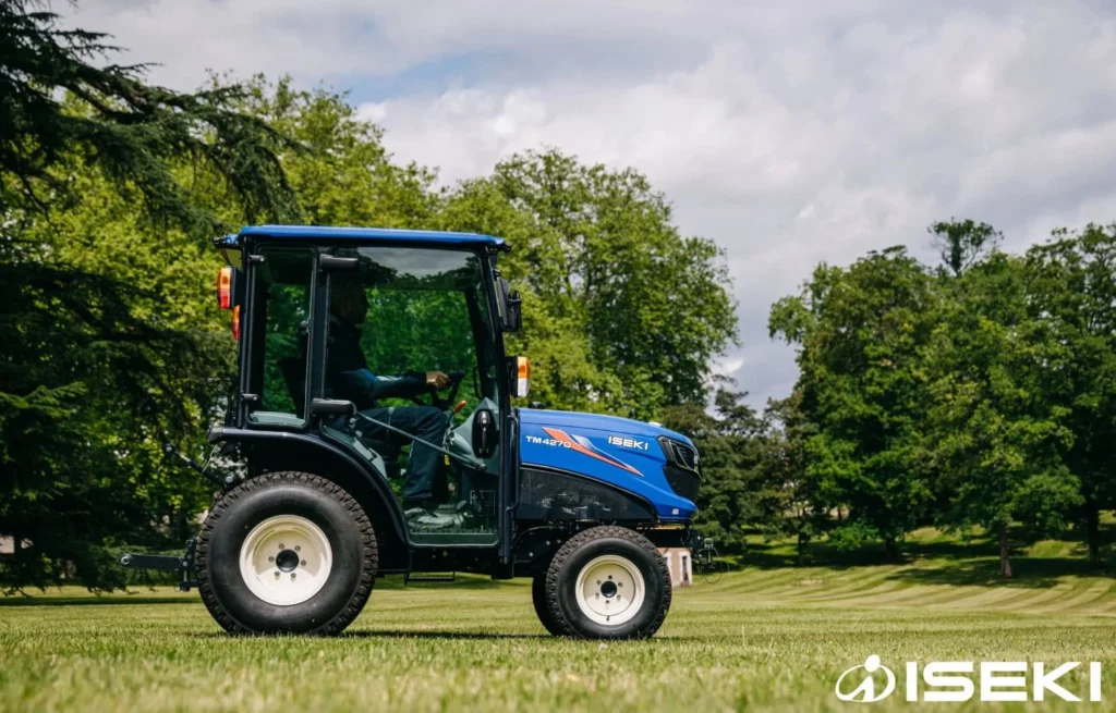Zijkant van de Iseki TM 4270 met cabine op een gemaaid grasveld