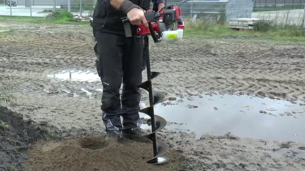 Grondboor kiezen: een eenmans benzine grondboor boort een gat in zandige grond voor een paal
