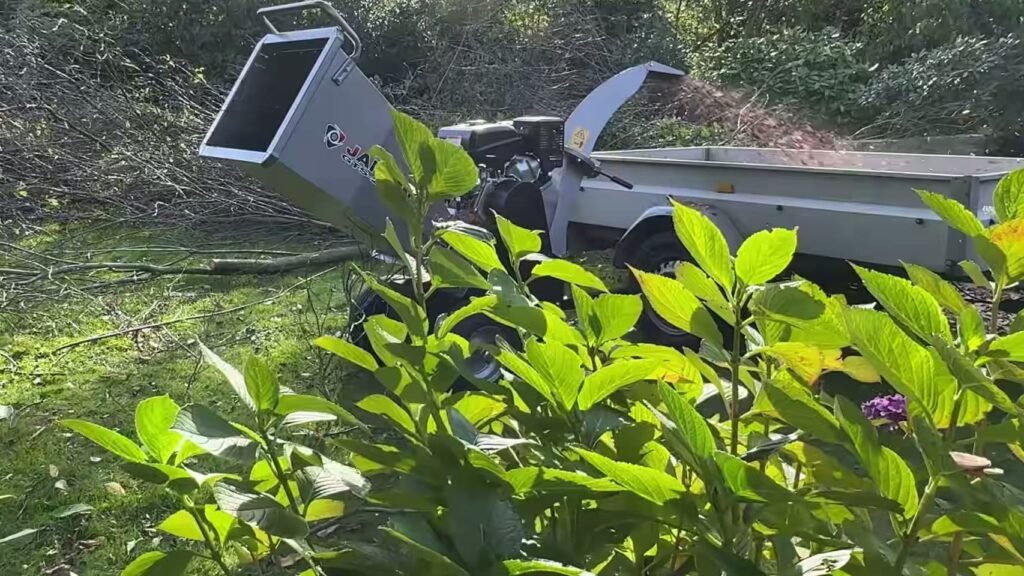 Hakselaar kiezen: Jansen GTS-2000pro blaast houtsnippers in een aanhanger naast een berg takken