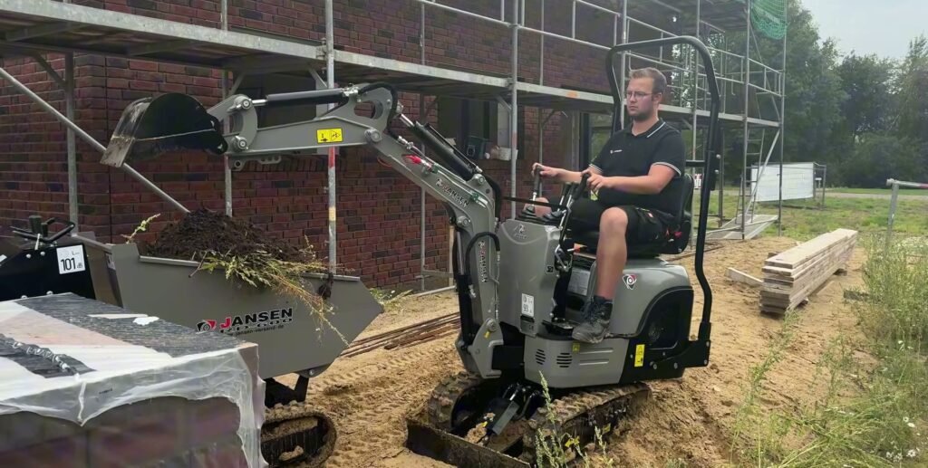 Jansen MB-800 op rubberen rupsen laadt grond in een kiepwagen naast een steiger
