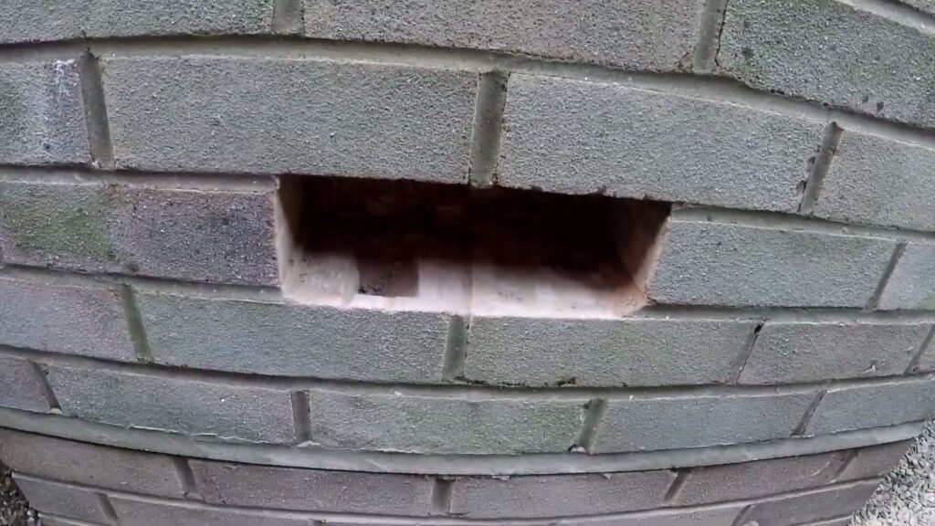 Uitgehakte opening in een bakstenen gevel, klaar voor een ventilatierooster