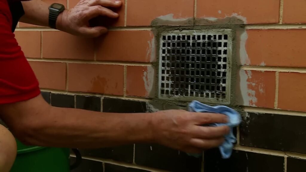Metalen ventilatierooster in een bakstenen gevel met afgewerkte voegen eromheen