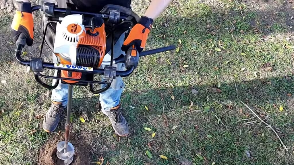STIHL BT 131 eenmans benzine grondboor met een spiraalboor in een gat in het gras
