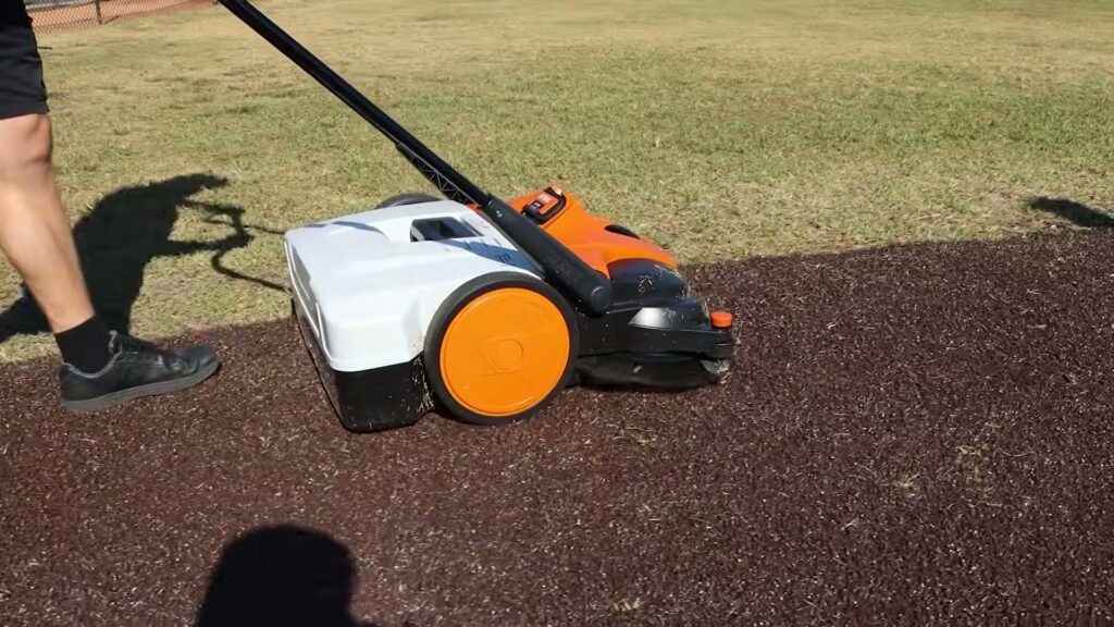 Accu handveegmachine van STIHL met opvangbak op een gazon en een rubberen ondergrond