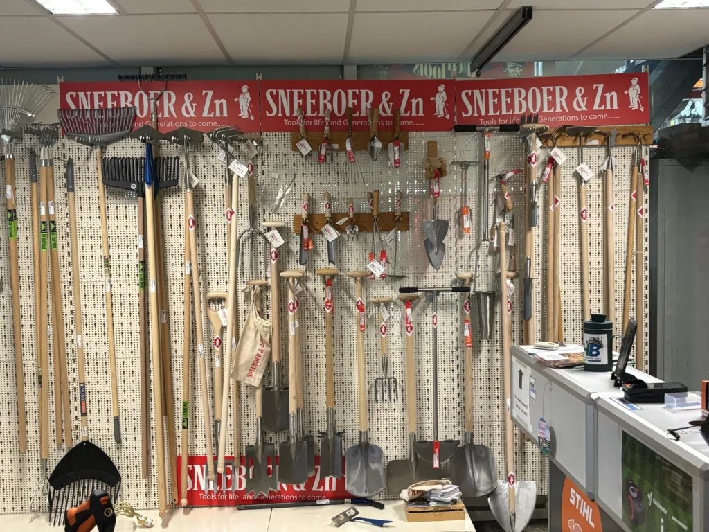 De wand met handgesmeed tuingereedschap van Sneeboer in de winkel